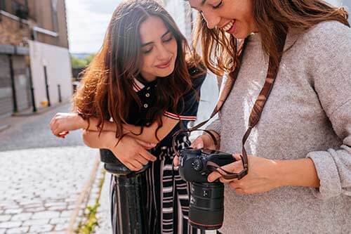 Two photographers smiling at the display of a Canon camera
