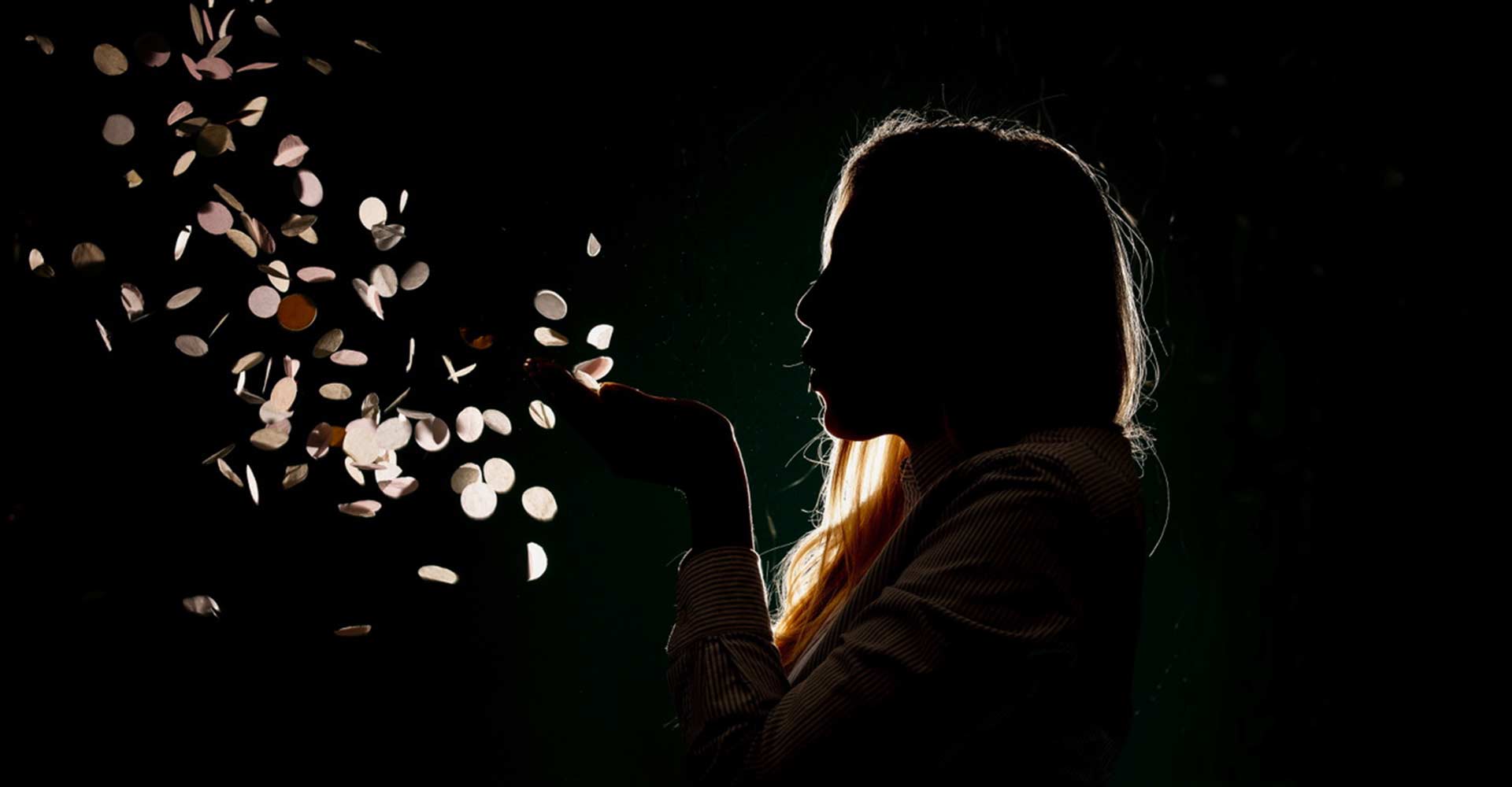 Woman blowing confetti in the dark